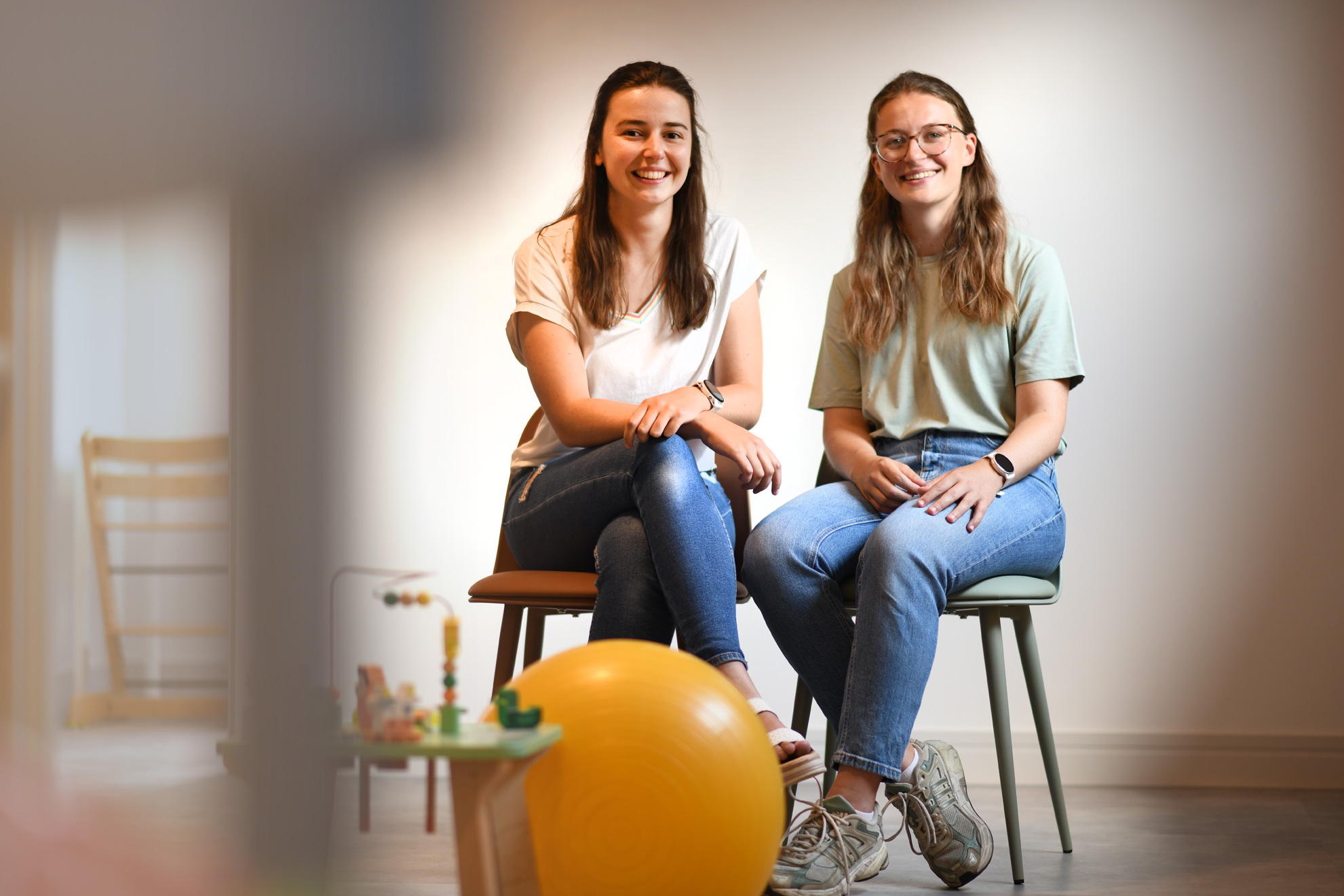 Een therapeute voert met een kind op de mat een oefening uit voor de beweeglijkheid van het been.
