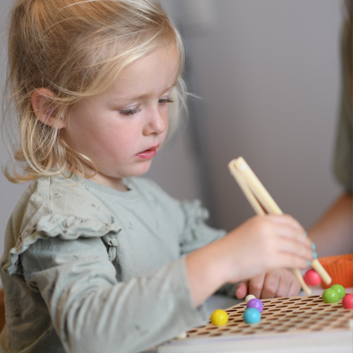 Een blond meisje tekent geconcentreerd met een pen op een whiteboard.